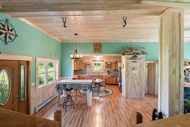 dining space with vaulted ceiling, sink, baseboard heating, and light hardwood / wood-style flooring