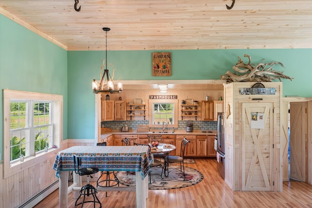 dining space with a baseboard heating unit, sink, a notable chandelier, wooden ceiling, and light hardwood / wood-style flooring