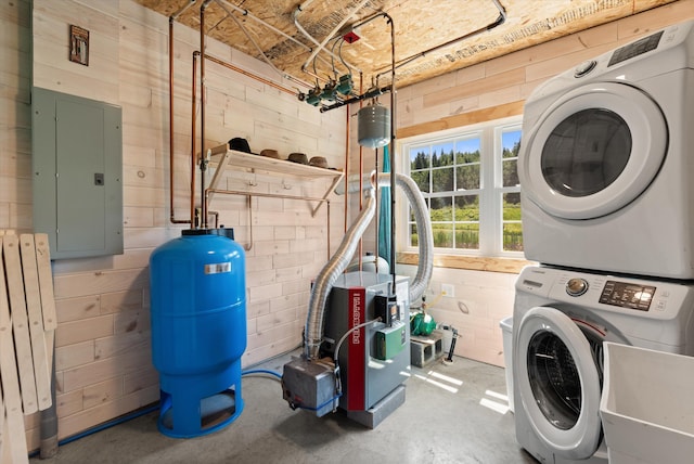 clothes washing area with stacked washer / drying machine, electric panel, sink, and wood walls