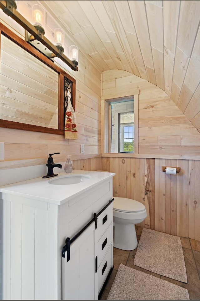 bathroom featuring wooden walls, lofted ceiling, vanity, toilet, and wooden ceiling