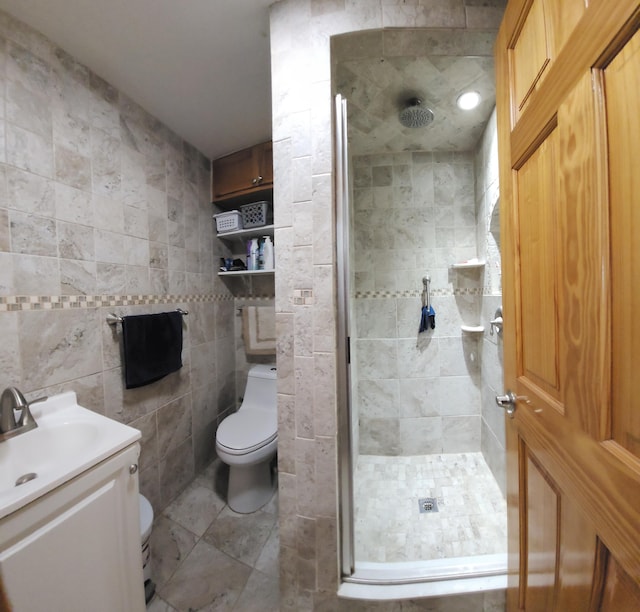 bathroom featuring toilet, vanity, tile walls, and a shower with door