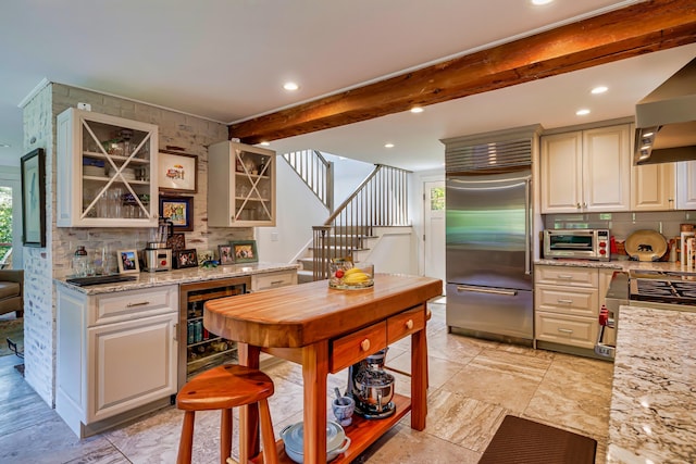 226 Graytown Rd, Sedgwick, ME 04676 - kitchen featuring tasteful backsplash, beam ceiling, beverage cooler, appliances with stainless steel finishes, and wall chimney exhaust hood