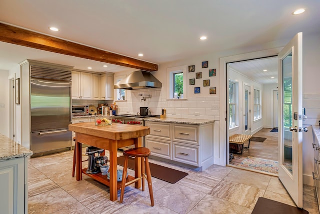 226 Graytown Rd, Sedgwick, ME 04676 - kitchen with beamed ceiling, wall chimney exhaust hood, tasteful backsplash, and stainless steel appliances