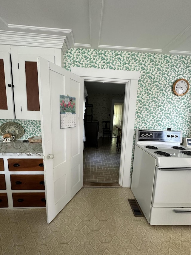 kitchen with white range with electric cooktop, ornamental molding, and white cabinetry