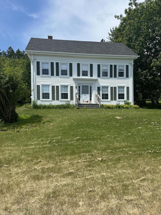 colonial-style house featuring a front lawn