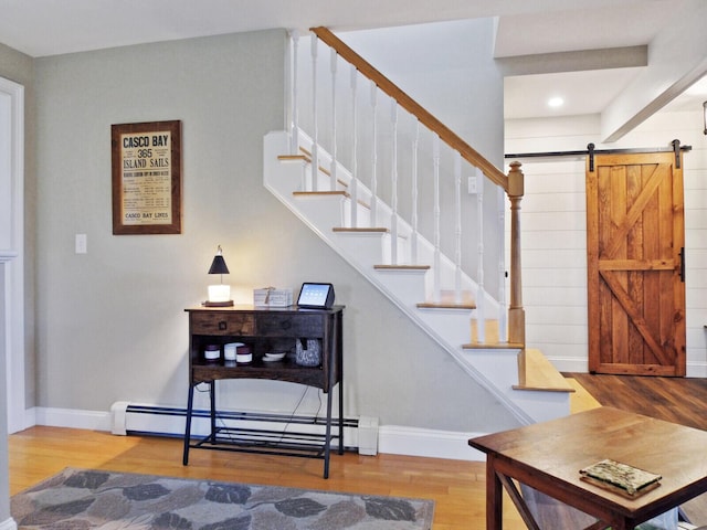 stairway featuring hardwood / wood-style floors, a barn door, and baseboard heating