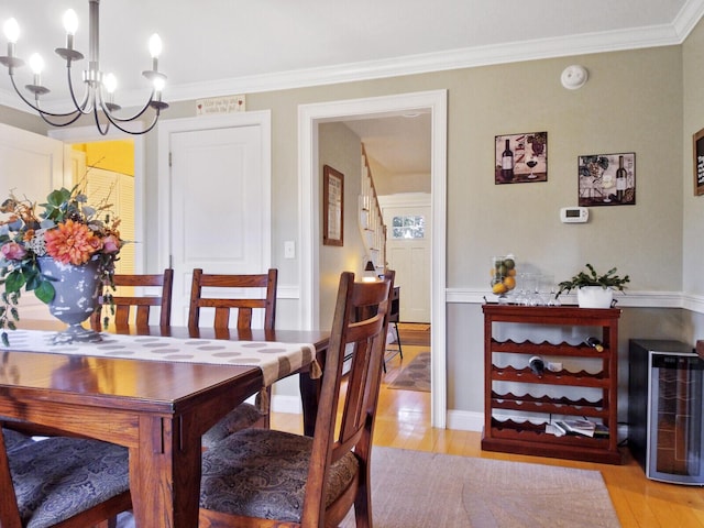 dining area featuring light hardwood / wood-style floors, wine cooler, ornamental molding, and a notable chandelier