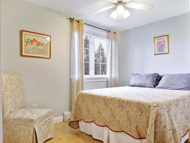 bedroom with hardwood / wood-style floors, a baseboard radiator, and ceiling fan