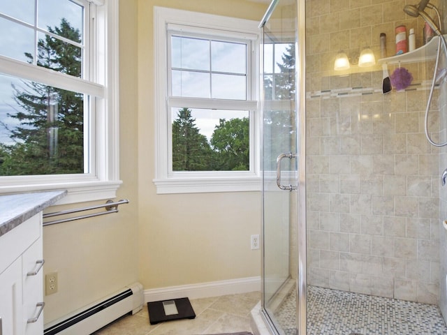 bathroom featuring tile patterned flooring, vanity, a shower with door, and a baseboard heating unit