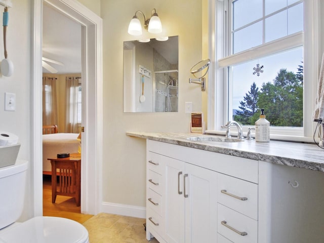 bathroom featuring ceiling fan with notable chandelier, vanity, toilet, and walk in shower