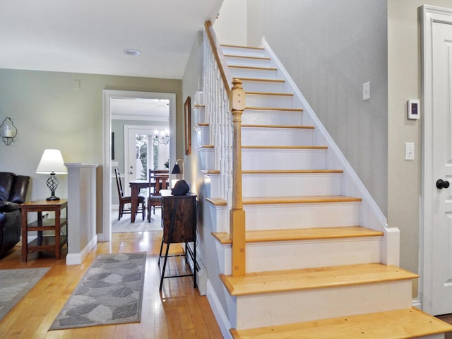 stairs with hardwood / wood-style floors, a chandelier, and ornamental molding