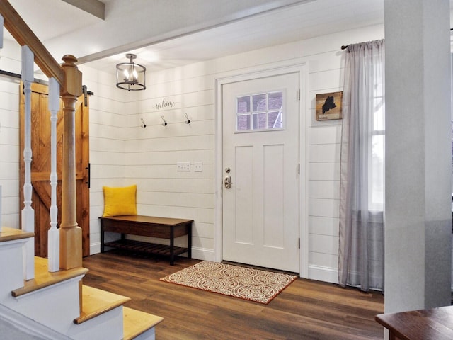 entryway with wood walls, a chandelier, and dark hardwood / wood-style floors