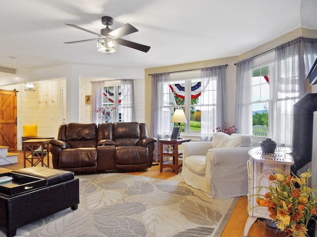 living room with a barn door, light hardwood / wood-style floors, and ceiling fan