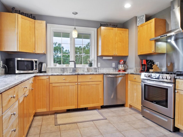 kitchen featuring wall chimney exhaust hood, light stone counters, sink, and appliances with stainless steel finishes