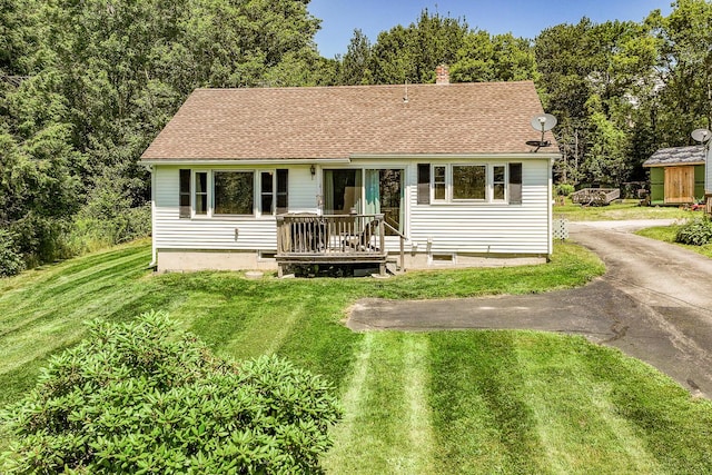 view of front of property with a shingled roof, a front yard, driveway, and a chimney