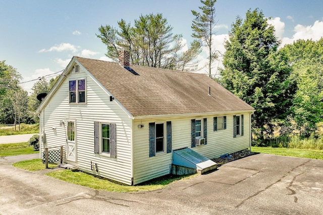 view of front of house featuring cooling unit, roof with shingles, and a chimney