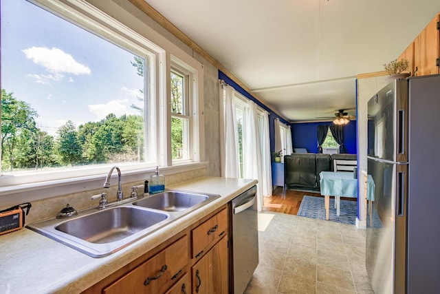 kitchen featuring ceiling fan, sink, appliances with stainless steel finishes, and ornamental molding