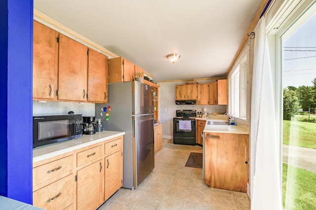 kitchen with black appliances, under cabinet range hood, light countertops, and a sink