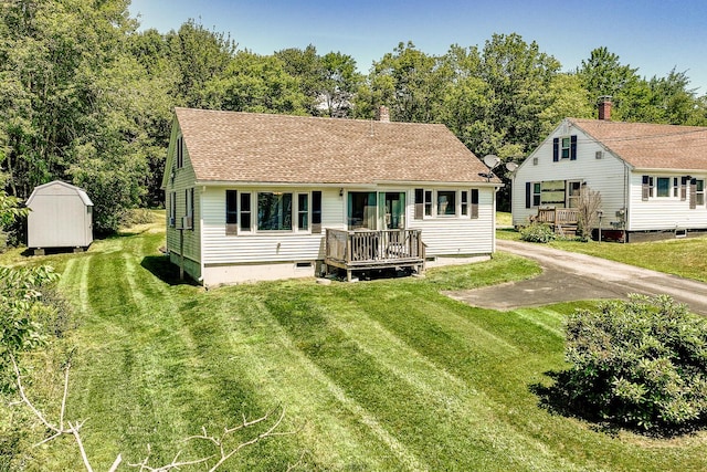 view of front facade with a front lawn, a storage unit, and a deck