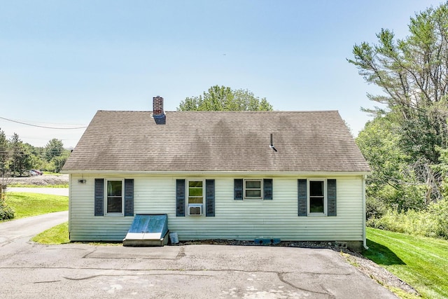 back of house with roof with shingles, a chimney, cooling unit, and a lawn