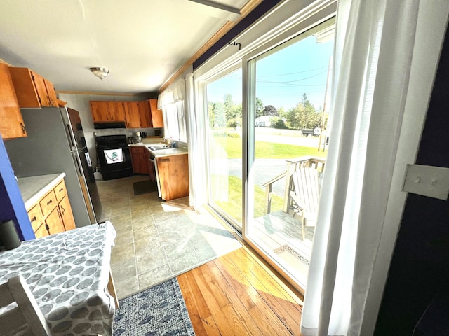 kitchen featuring sink, stainless steel refrigerator, stove, and light wood-type flooring