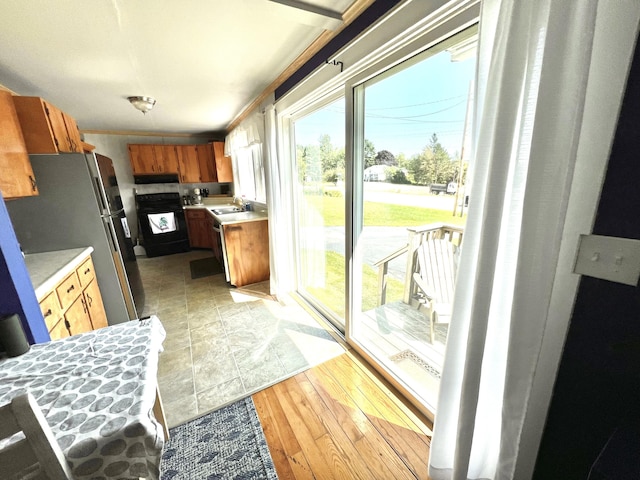 kitchen with black range oven, freestanding refrigerator, light countertops, and a sink