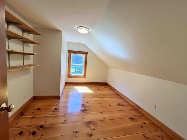 additional living space featuring vaulted ceiling and light hardwood / wood-style floors