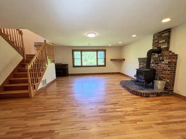 unfurnished living room featuring a wood stove and light hardwood / wood-style floors