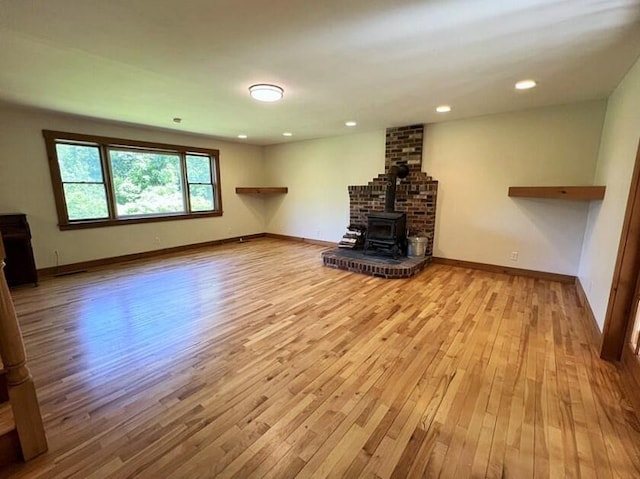 unfurnished living room featuring a wood stove and light hardwood / wood-style floors