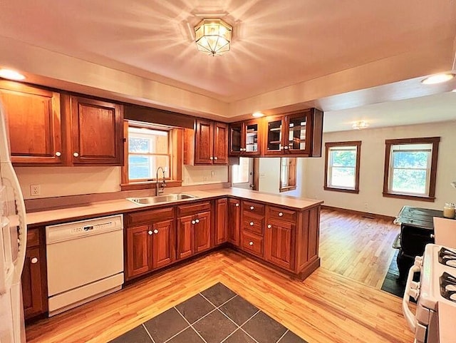 kitchen with kitchen peninsula, sink, white appliances, and light hardwood / wood-style floors