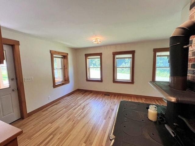 unfurnished living room with a wood stove and light wood-type flooring