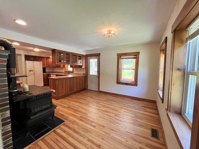 kitchen with sink, white fridge with ice dispenser, light hardwood / wood-style flooring, and kitchen peninsula