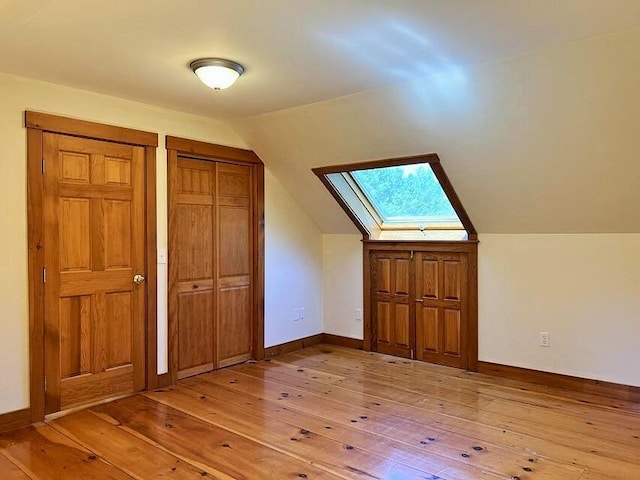 bonus room featuring vaulted ceiling with skylight and light hardwood / wood-style floors