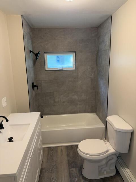 full bathroom featuring vanity, toilet, tiled shower / bath combo, and hardwood / wood-style flooring