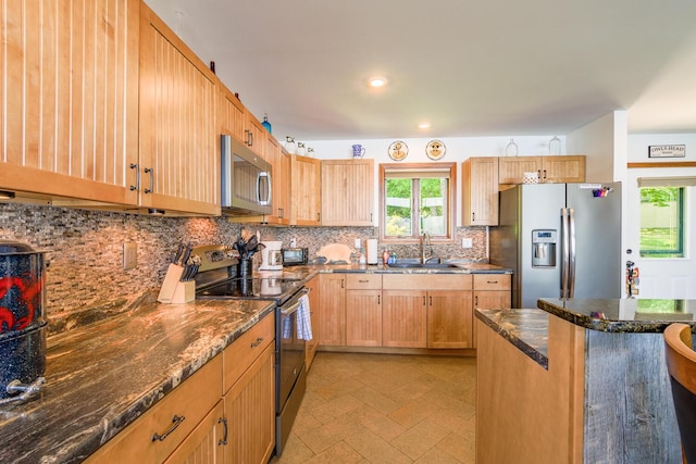 kitchen with recessed lighting, stainless steel appliances, a sink, decorative backsplash, and dark stone countertops