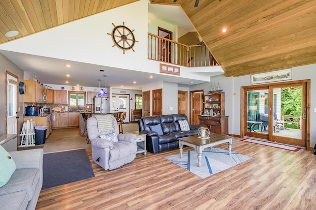 living area featuring a healthy amount of sunlight, light wood-style floors, and wooden ceiling