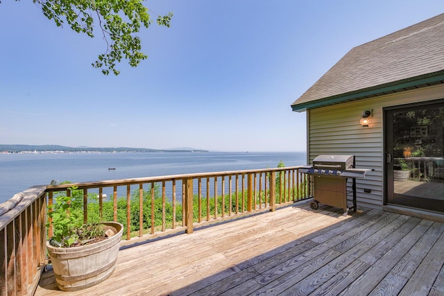 wooden terrace featuring a water view and a grill
