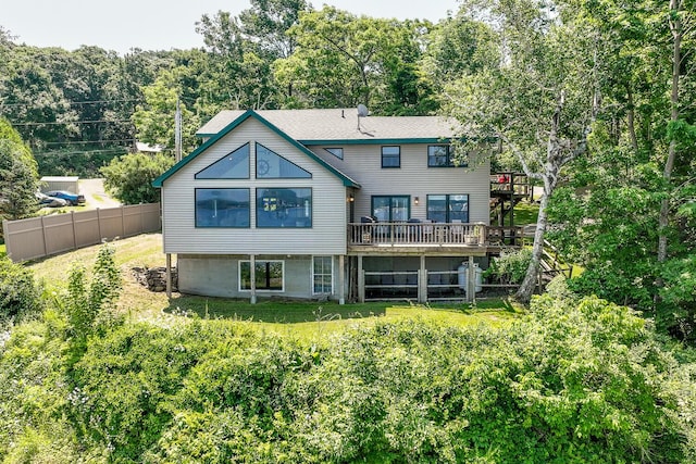 back of house featuring a lawn, a wooden deck, and fence