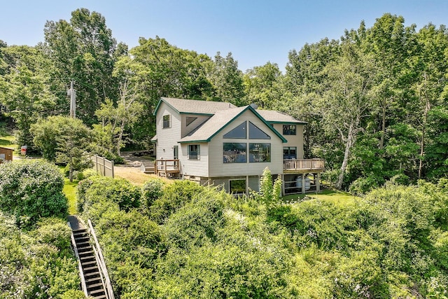 rear view of property with a forest view, a shingled roof, and a wooden deck