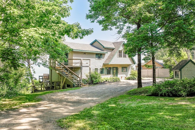 view of front of property featuring a shingled roof, a front yard, fence, and stairs