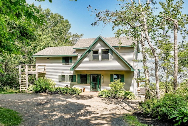 view of front of home with stairway and roof with shingles