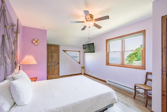 bedroom featuring baseboard heating, vaulted ceiling, ceiling fan, wood finished floors, and baseboards