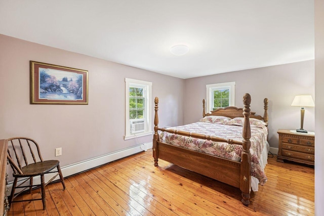 bedroom with light wood-type flooring, multiple windows, and a baseboard heating unit