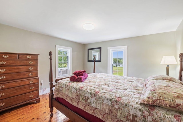 bedroom featuring multiple windows, cooling unit, and light wood-type flooring