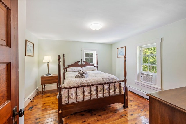 bedroom featuring cooling unit, light wood-type flooring, and a baseboard radiator