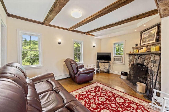 living room with beamed ceiling, light hardwood / wood-style floors, a stone fireplace, and a healthy amount of sunlight