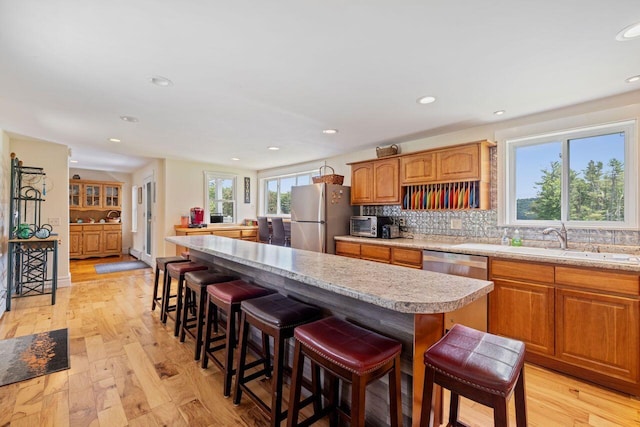 kitchen featuring a breakfast bar, sink, light wood-type flooring, a kitchen island, and stainless steel appliances