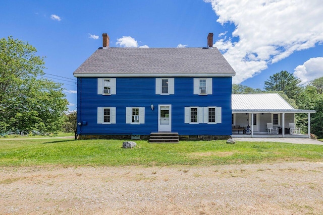 rear view of house featuring a lawn and covered porch