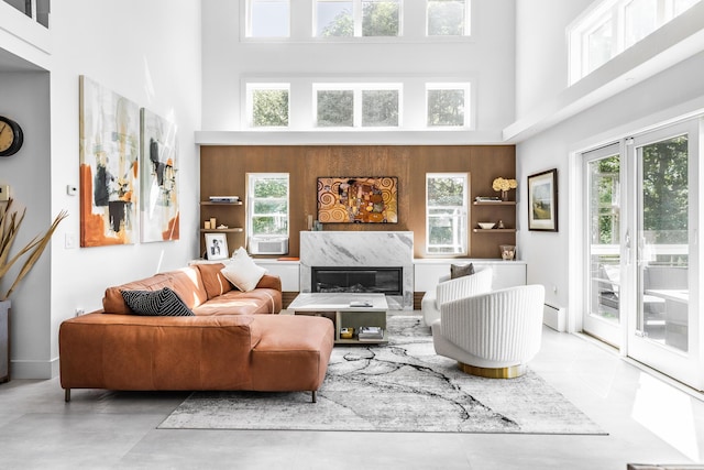 living room featuring a wealth of natural light, a high end fireplace, a high ceiling, and a baseboard radiator