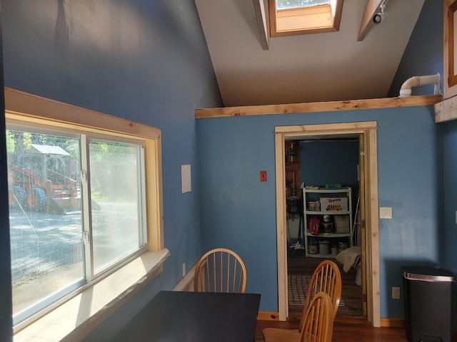 dining space with hardwood / wood-style floors and lofted ceiling with skylight